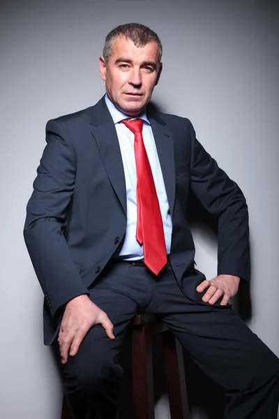 Mid aged business man sitting on a stool — Stock Photo, Image