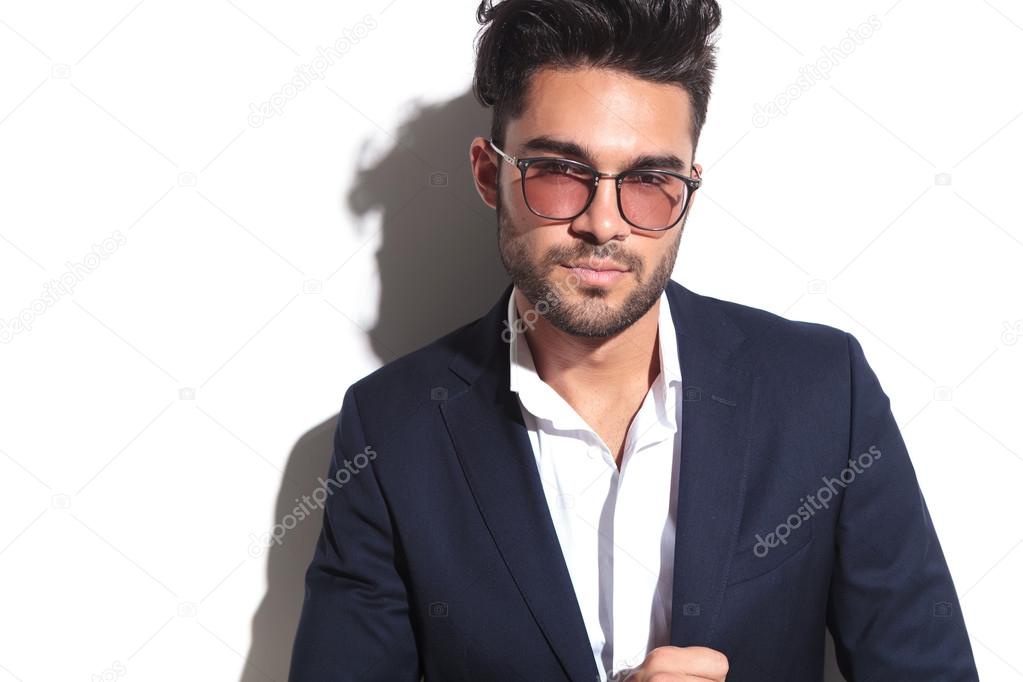 Young business man wearing sunglasses looking at the camera 
