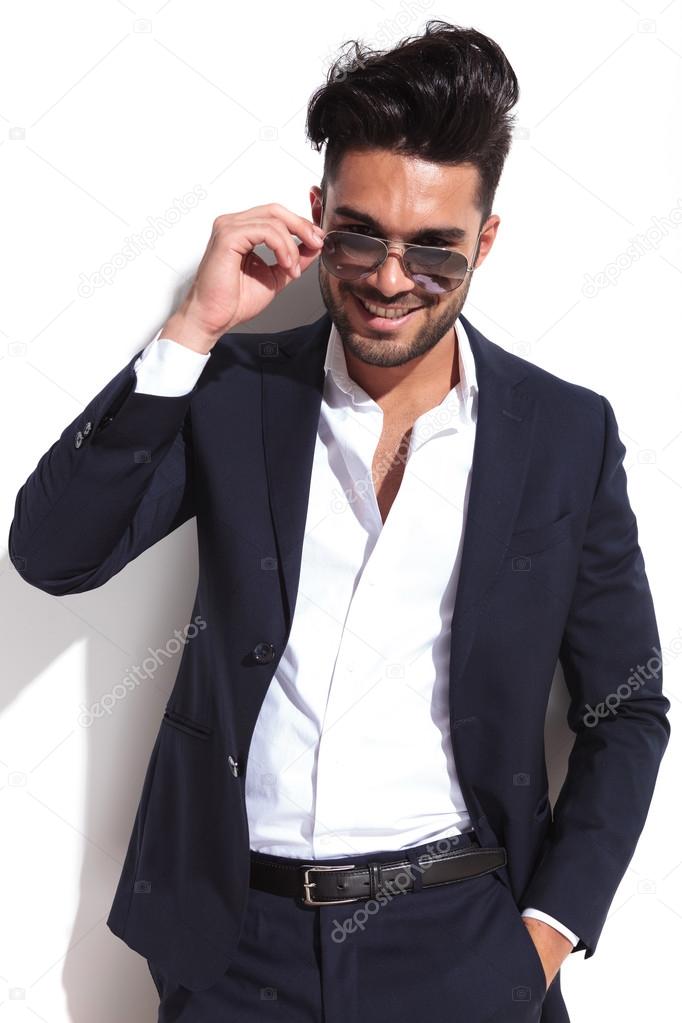 Smiling business man putting on his sunglasses