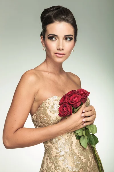 Egy gyönyörű nő, arany ruha rózsákkal oldalán — Stock Fotó