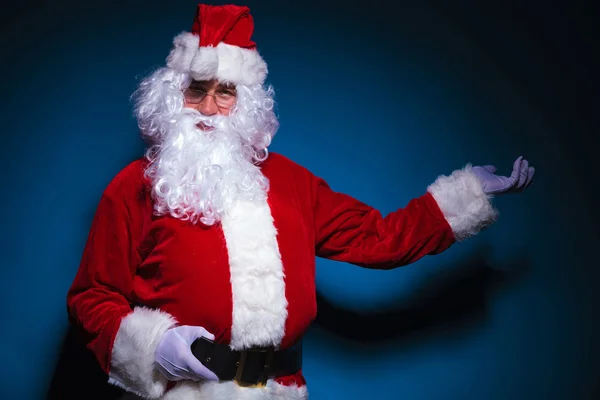 Mikołajem przedstawiając na niebieski backgrorund — Zdjęcie stockowe