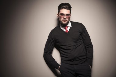 Gri bir duvara yaslanmış yakışıklı iş adamı