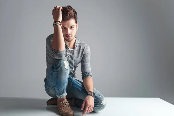 Uomo seduto sul pavimento mentre fissa i capelli — Foto Stock