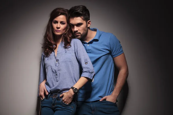 Fashion couple leaning embraced on a grey wall — Stock Photo, Image