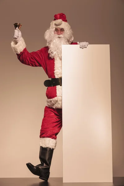 Père Noël tenant une cloche et un panneau blanc — Photo