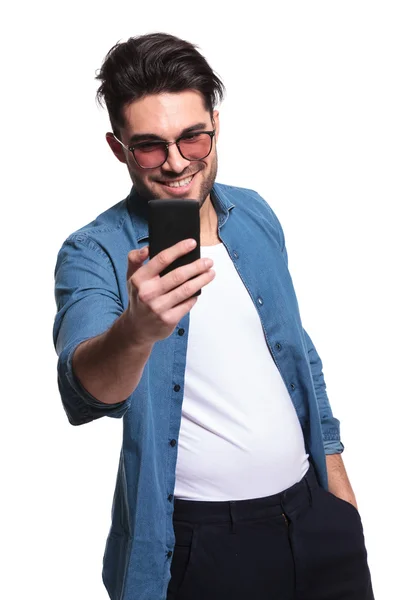 Jovem casual homem sorrindo enquanto mensagens — Fotografia de Stock