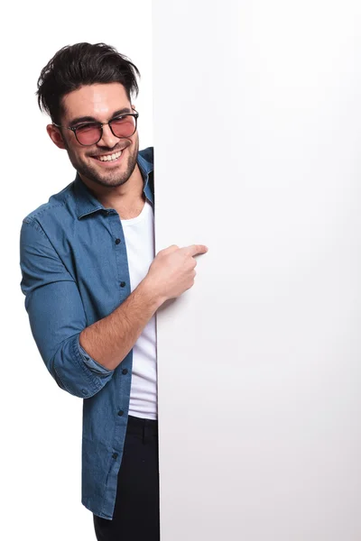 Young casual man pointing to a empty board — Stock Photo, Image