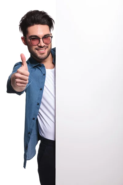 Jovem homem casual apresentando uma placa branca — Fotografia de Stock