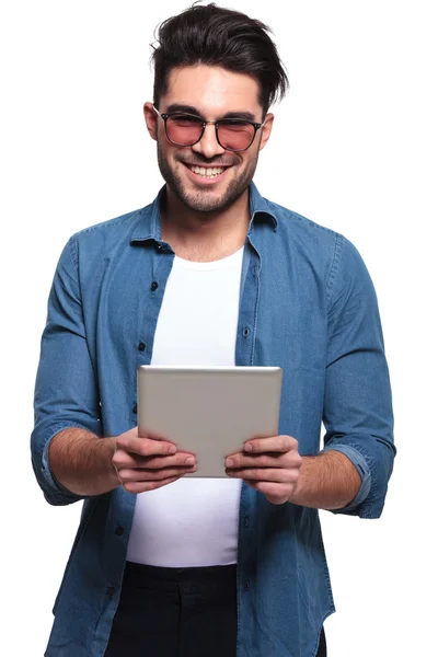 Uomo sorridente mentre tiene in mano un tablet del computer — Foto Stock