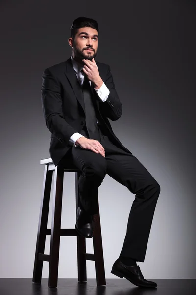 Young business man fixing his beard, thinking — Stock Photo, Image