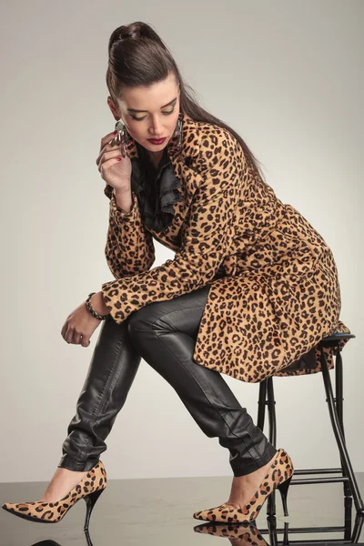 Jovem mulher da moda olhando para baixo enquanto sentado — Fotografia de Stock