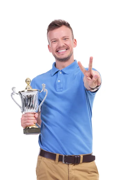 Casual young man with trophy shows victory sign — Stock Photo, Image