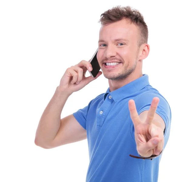 Casual young man shows victory over the phone — Stock Photo, Image