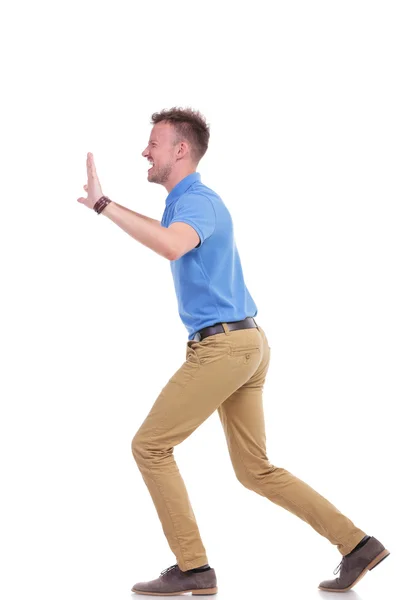 Casual young man pushes something imaginary — Stock Photo, Image