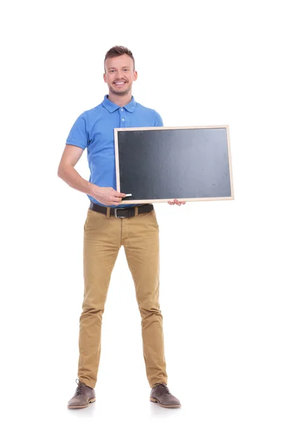 Casual young man points with chalk at blackboard — Stock Photo, Image