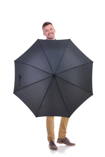 Lässiger junger Mann hinter einem schwarzen Regenschirm — Stockfoto