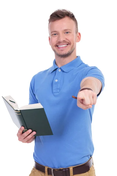 Young casual man with book points at you — Stock Photo, Image