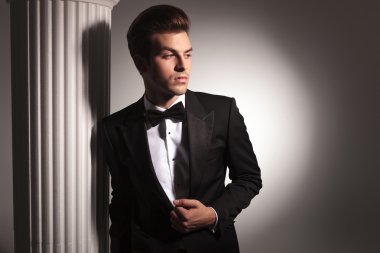 Beyaz bir sütun üzerinde eğilim genç iş adamı