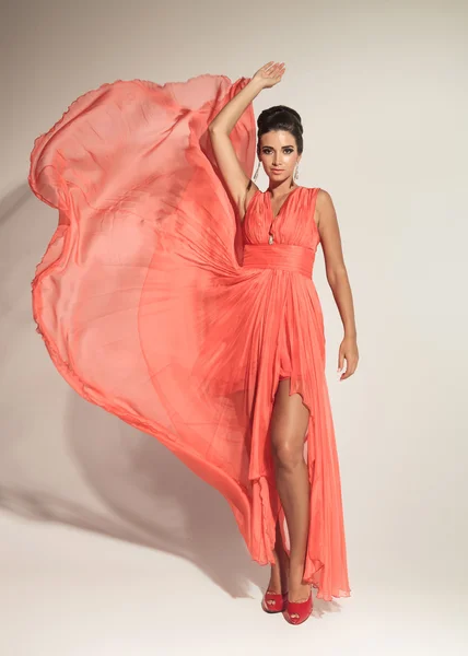 Elegant fashion woman fluttering her coral dress — Stock Photo, Image