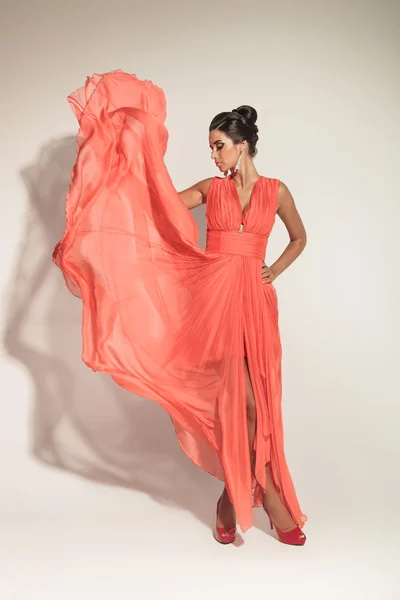 Fashion woman looking down while fluttering her coral dress — Stock Photo, Image