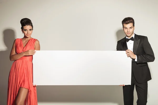 Fashion man and woman holding a blank board. — Stock Photo, Image
