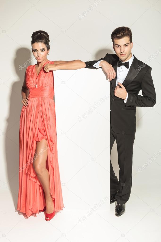 fashion couple leaning on a white empy board