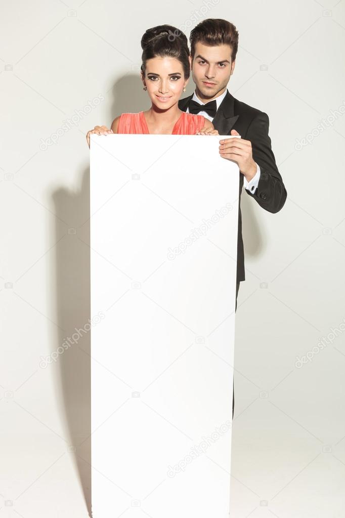 Elegant fashion couple holding a white empty board