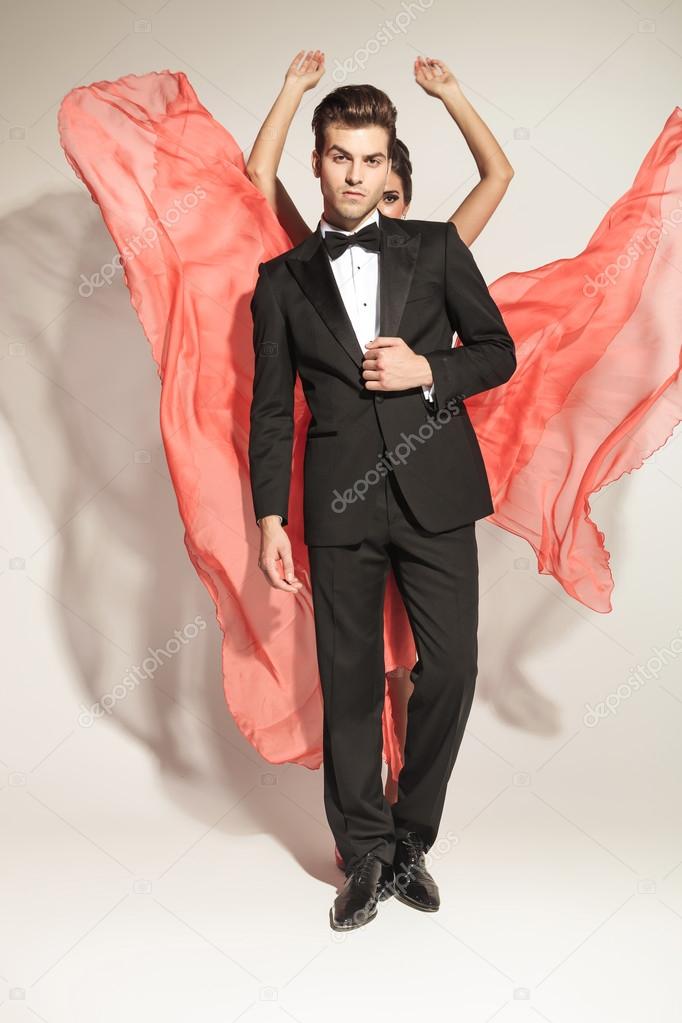 man fixing tuxedo while his lover is fluttering her dress