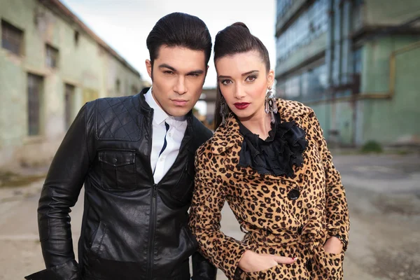 Young fashion couple posing, both holding hands in pockets. — Stock Photo, Image