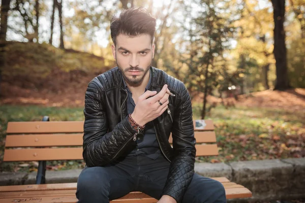 Mode man zittend op een bankje in het park — Stockfoto