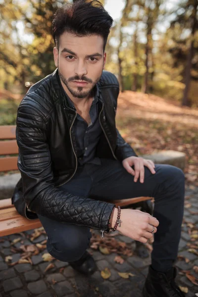 Mode man zittend op een bankje in het park. — Stockfoto