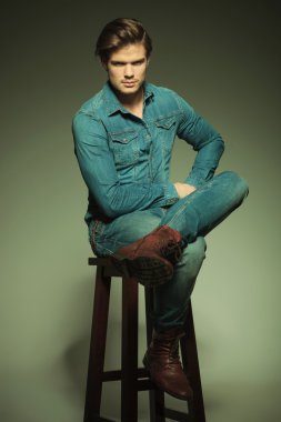 Bacaklarını çapraz bir taburede oturan casual adam