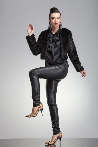 Mode kvinna poserar med ett ben och en hand upp. — Stockfoto
