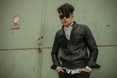 Yeşil metal kapıya yaslanmış moda adam