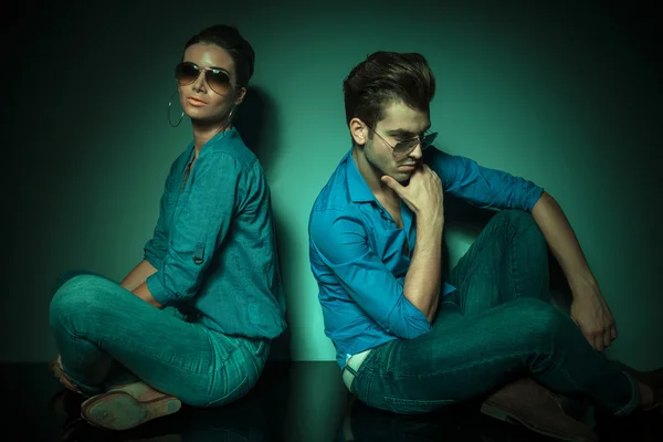 Man and fashion woman sitting back to back — Stock Photo, Image