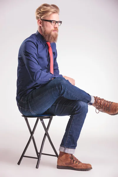 Young casual man sitting on a stool — Stock Photo, Image