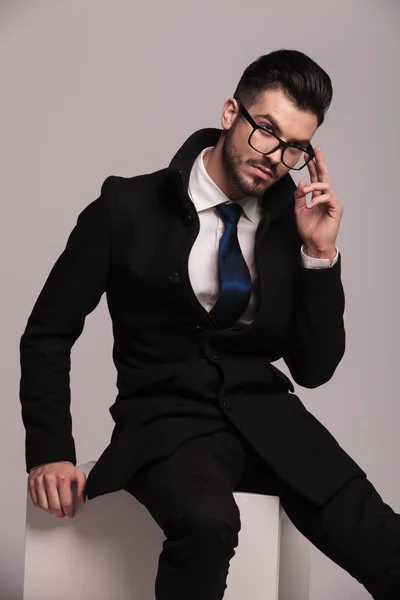 Elegante hombre de negocios sentado en un cubo blanco — Foto de Stock