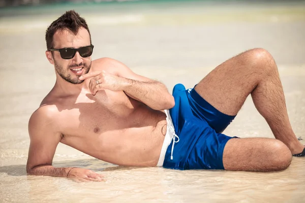 Hot young man lying on the beach — Stock Photo, Image