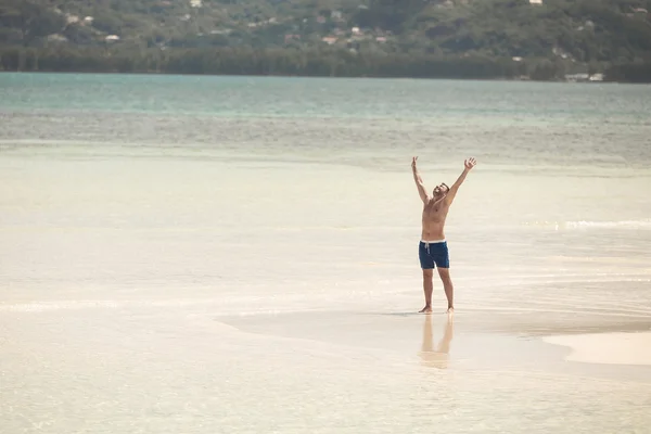 Homem feliz na praia segurando as duas mãos para cima — Fotografia de Stock