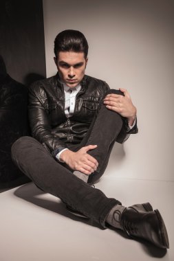 Stüdyo arka plan üzerinde oturan yakışıklı genç casual adam 