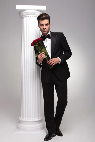 Elegáns üzletember, kezében egy csokor vörös rózsa — Stock Fotó