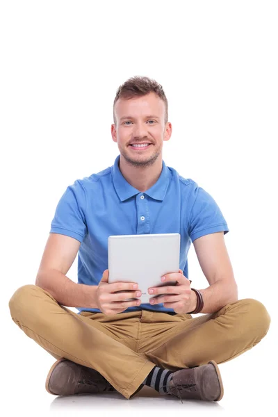 Sittande ung man håller sin tablet — Stockfoto