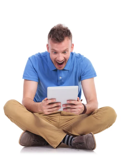 Sittande ung man chockad av sin tablett — Stockfoto
