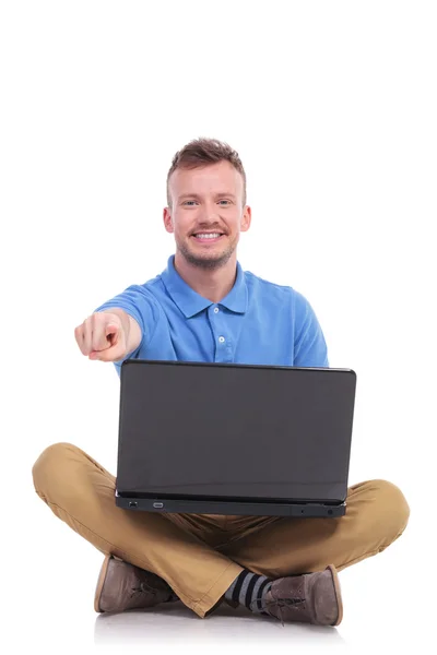 Jovem sentado homem com laptop aponta para você — Fotografia de Stock
