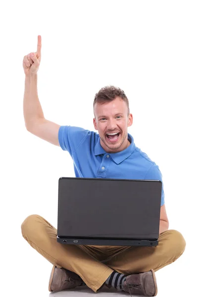 Jovem sentado homem com laptop aponta para cima — Fotografia de Stock