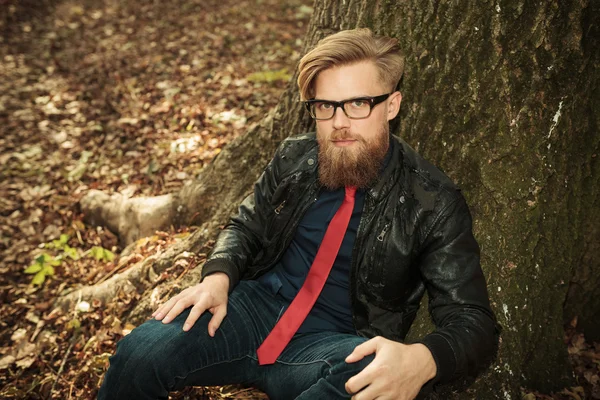 Мужчина с белокурой бородой сидит возле дерева — стоковое фото