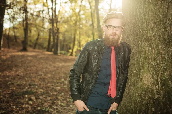 Mann lehnt mit den Händen in den Taschen an einem Baum. — Stockfoto