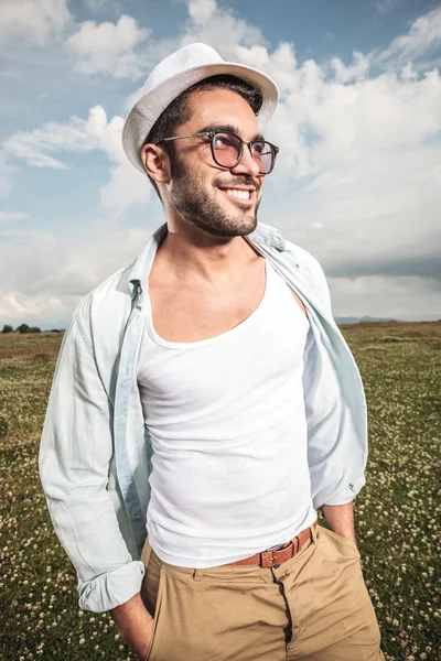 Молодой счастливый человек позирует в поле с цветами — стоковое фото