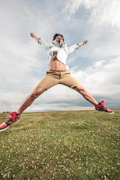 Genç adam bir sahada atlama tam çiçek — Stok fotoğraf