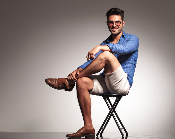 casual young fashion man sitting with his legs crossed